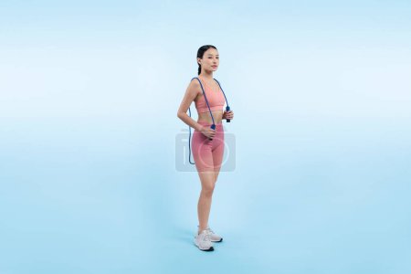 Foto de Joven mujer asiática enérgica en ropa deportiva con salto o saltarse la bata posando retrato en estudio filmado en un fondo aislado. Herramienta de ejercicio cardiovascular y estilo de vida saludable para el cuidado corporal. Vigoroso - Imagen libre de derechos