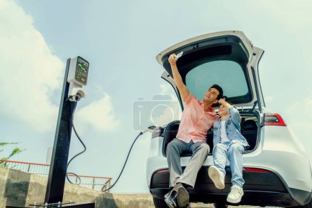Photo for Family road trip vacation traveling with electric car, father and son recharge EV car with green and clean energy. Natural travel and eco-friendly car for sustainable environment. Perpetual - Royalty Free Image