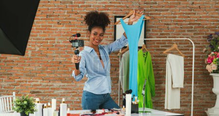 Photo for Woman influencer shoot live streaming vlog video review clothes crucial social media or blog. Happy young girl with apparel studio lighting for marketing recording session broadcasting online. - Royalty Free Image