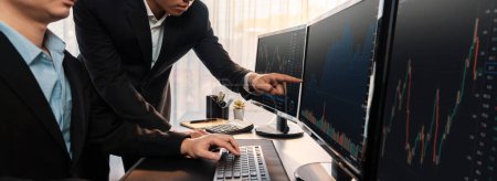 Photo for Group of traders discussing on office desk, monitoring stock market on monitor at office workplace. Businessman and broker analyzing stock graph together at stock trading company. Trailblazing - Royalty Free Image