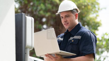 Photo for Qualified technician working on home EV charging station installation, making troubleshooting and configuration setup on charging system with laptop for EV at home. Synchronos - Royalty Free Image