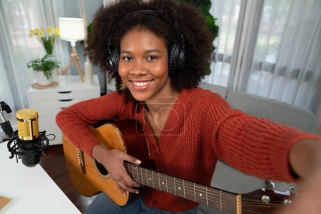 Téléchargez les photos : Chaîne hôte en musicien de jeune afro-américain avec selfie pour les fans, diffusion sur smartphone en studio privé. Décoration de l'équipement des casques et microphone enregistreur. Tastemaker. - en image libre de droit