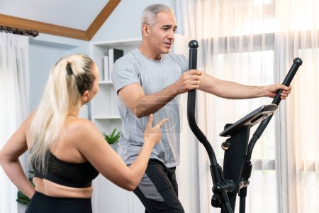 Photo for Active senior couple running on elliptical running machine at home together as fitness healthy lifestyle and body care after retirement for pensioner. Clout - Royalty Free Image