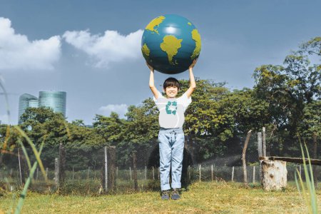 Téléchargez les photos : Jeune garçon asiatique tenant grande planète globe terrestre au parc naturel avec fond de ciel comme jour de la Terre pour sauver cette planète avec le principe ESG et l'énergie respectueuse de l'environnement pour un avenir plus brillant. Pneumatique - en image libre de droit