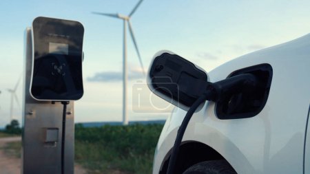 Téléchargez les photos : Concept progressif d'infrastructure énergétique future de recharge du véhicule électrique à la borne de recharge alimentée par des énergies vertes et renouvelables à partir d'une éolienne afin de préserver l'environnement. - en image libre de droit