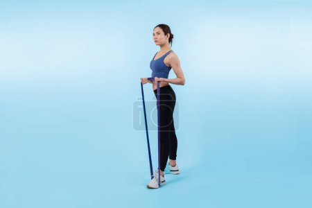 Photo for Vigorous energetic woman in sportswear portrait stretching resistance sport band. Young athletic asian woman strength and endurance training session workout routine concept on isolated background. - Royalty Free Image