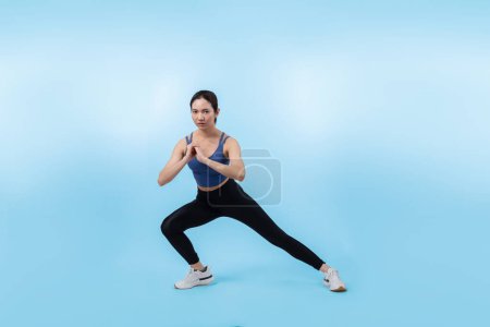 Téléchargez les photos : Jeune femme asiatique attrayante en vêtements de sport étirement avant la routine d'exercice de remise en forme. Exercice de soin du corps sain avec femme athlétique échauffement sur fond isolé prise de vue en studio. Vigoureux - en image libre de droit