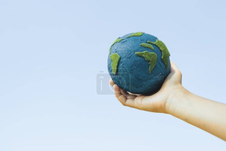 Photo for Young boys hand holding planet Earth globe with sky and cloudscape background as Earth day to save this planet with ESG principle and environment friendly energy for brighter future. Gyre - Royalty Free Image