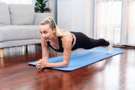 Photo for Athletic and sporty senior woman planking on fitness exercising mat at home exercise as concept of healthy fit body lifestyle after retirement. Clout - Royalty Free Image