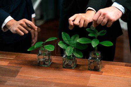 Photo for Business people put money saving into jar filled with coins and growing plant for sustainable financial planning for retirement or eco subsidy investment for environment protection. Quaint - Royalty Free Image