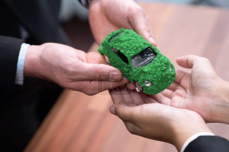 Téléchargez les photos : Les hommes d'affaires échangent et tiennent éco modèle de voiture verte. Véhicule électrique utilisé par la société écologique pour le transport respectueux de l'environnement. Entreprise zéro émission de CO2 responsable. Charmante. - en image libre de droit