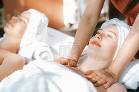 Photo for A portrait of two beautiful woman having back massage by professional masseur and falling in deep relaxation surrounded by traditional spa environment. Calming and relaxing concept. Tranquility. - Royalty Free Image