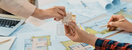 Photo for Professional engineer and architect collaborate on eco house project at meeting table with green design blueprint and architectural equipment at modern office. Focus on hand. Close up. Delineation. - Royalty Free Image