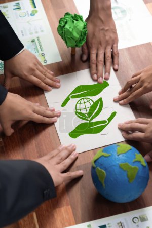 Téléchargez les photos : Groupe cohérent de gens d'affaires formant des pièces de puzzle dans le symbole de sensibilisation à l'environnement en tant que responsabilité environnementale de l'entreprise pour la communauté et une solution durable pour une Terre plus verte. Charmante. - en image libre de droit
