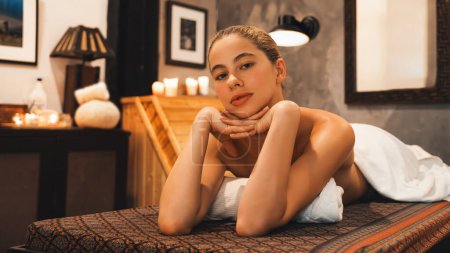 Photo for Portrait of beautiful caucasian woman in white towel woman lies on spa bed in front of warm wooden sauna cabinet with relaxation and peaceful at spa salon. Close up. A Side view. Tranquility. - Royalty Free Image