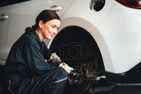 Téléchargez les photos : Mécanicien féminin travailleur changeant de roue de voiture dans l'atelier de réparation automobile. Travailleur d'entretien automobile changer les pneus en caoutchouc qui fuient dans le concept d'entretien de voiture professionnelle et d'entretien. Oxus - en image libre de droit