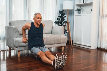 Photo for Athletic and active senior man using furniture for effective targeting muscle with push up at home exercise as concept of healthy fit body lifestyle after retirement. Clout - Royalty Free Image