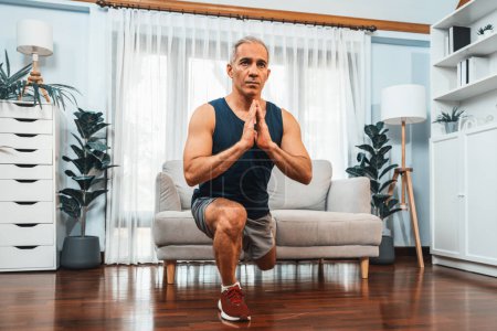 Photo for Active and fit senior man warmup and stretching using furniture before home exercising routine at living room. Healthy fitness lifestyle concept after retirement for pensioner. Clout - Royalty Free Image