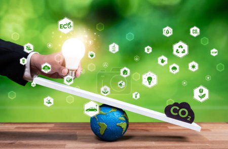 Photo for Businessman balance light bulb on scale with CO2 emission icon, demonstrate concept of ESG commitment and environmental conservative idea to carbon reduction through clean energy technology. Reliance - Royalty Free Image