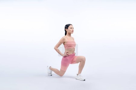 Foto de Joven atractiva mujer asiática en ropa deportiva estiramiento antes de la rutina de ejercicios de fitness. Ejercicio de cuidado del cuerpo saludable con la mujer atlética calentando en estudio tiro fondo aislado. Vigoroso - Imagen libre de derechos