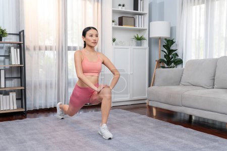 Photo for Young attractive asian woman in sportswear stretching before fitness exercise routine. Home body workout with healthy athletic woman warming up. Vigorous - Royalty Free Image