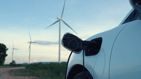 Téléchargez les photos : Concept progressif d'infrastructure énergétique future de recharge du véhicule électrique à la borne de recharge alimentée par des énergies vertes et renouvelables à partir d'une éolienne afin de préserver l'environnement. - en image libre de droit