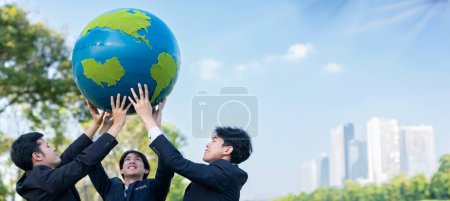 Téléchargez les photos : Concept de journée de la Terre avec grand globe terrestre tenu par un groupe de gens d'affaires asiatiques équipe de promotion de la sensibilisation à l'environnement avec la durabilité environnementale et le principe ESG pour un avenir plus brillant. Pneumatique - en image libre de droit