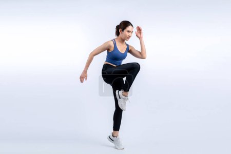 Photo for Side view young athletic asian woman on running posture in studio shot on isolated background. Pursuit of healthy fit body physique and cardio workout exercise lifestyle concept. Vigorous - Royalty Free Image