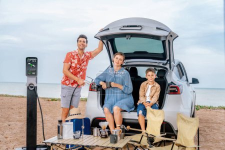Photo for Family vacation trip traveling by the beach with electric car, happy family recharge EV car, enjoying outdoor camping coffee. Seascape travel and eco-friendly car for clean environment. Perpetual - Royalty Free Image