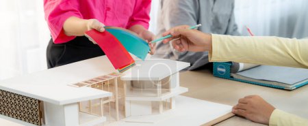 Photo for Cropped image of skilled architect and interior designer team collaborate to select house color theme at meeting room with house model placed on table. Creative working and design concept. Variegated. - Royalty Free Image