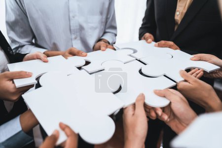 Photo for Diverse corporate officer workers collaborate in office, connecting puzzle pieces to represent partnership and teamwork. Unity and synergy in business concept by merging jigsaw puzzle. Concord - Royalty Free Image