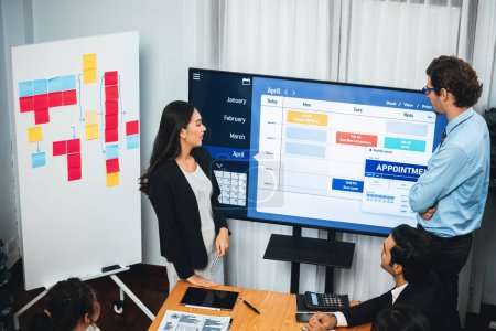 Photo for Project manager planning schedules for business task at meeting room, Gantt chart software show on TV screen. Multi ethnic diversity business people and modern business project management. Meticulous - Royalty Free Image