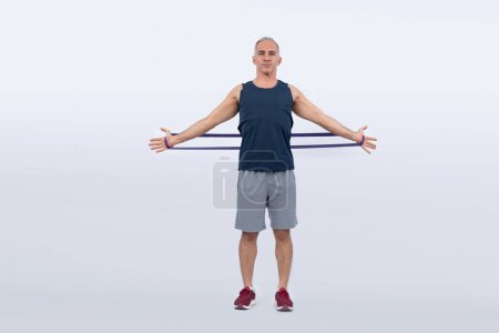 Photo for Full body length shot athletic and sporty senior man with fitness resistance band on isolated background. Healthy active physique and body care lifestyle after retirement. Clout - Royalty Free Image