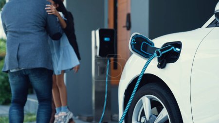 Photo for Modern family with young girl recharge electric car, EV charger from home charging station plugged in EV car in house garage. Smart and futuristic home energy infrastructure. Peruse - Royalty Free Image