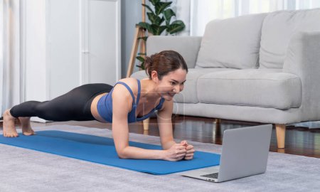 Photo for Fit young asian woman planing on the living room floor while following exercise instruction on online training video. Healthy lifestyle workout routine at home. Balance and endurance concept. Vigorous - Royalty Free Image
