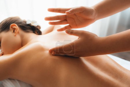 Téléchargez les photos : Grosse cliente profitant d'un massage spa relaxant anti-stress et dorlotant avec des loisirs de beauté de la peau dans le spa de salon d'ambiance de lumière du jour au complexe de luxe ou à l'hôtel. Tranquillité - en image libre de droit