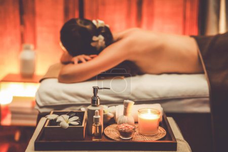 Photo for Aromatherapy massage ambiance or spa salon composition setup with focus decor candles and spa accessories on blurred woman enjoying blissful aroma spa massage in resort or hotel background. Quiescent - Royalty Free Image