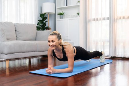 Foto de Mujer mayor atlética y deportiva planking en la alfombra de ejercicio de fitness en el ejercicio en casa como concepto de estilo de vida corporal en forma saludable después de la jubilación. Clout. - Imagen libre de derechos