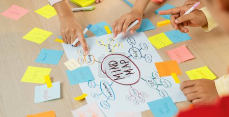 Photo for Creative business team brainstorming about marketing strategy and business plan by using mind mapping. Startup team work together to write down on paper. Focus on hand. Closeup. Variegated. - Royalty Free Image