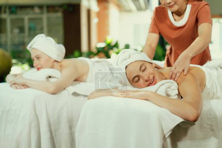 Téléchargez les photos : Un portrait de deux jeunes femmes séduisantes allongées sur le lit lors d'un massage du dos par un masseur professionnel en plein air entouré d'un environnement naturel paisible. Concept santé et beauté. Tranquillité. - en image libre de droit