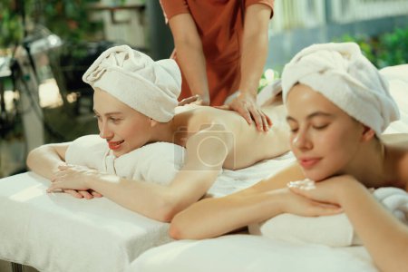 Photo for Couple of beautiful young woman lie on white spa bed during having back massage. Attractive caucasian woman having back massage at traditional spa room. Relaxing and healthy concept Tranquility. - Royalty Free Image