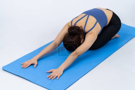 Photo for Asian woman in sportswear doing yoga exercise on fitness mat as her workout training routine. Healthy body care and calm meditation in yoga lifestyle in full body shot on isolated background. Vigorous - Royalty Free Image