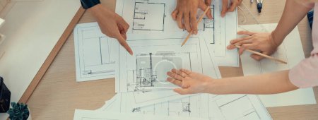 Photo for Skilled architect engineer team and interior designer meeting presents house construction on table with blueprint and architectural equipment.scatter around. Focus on hand. Top view. Burgeoning. - Royalty Free Image