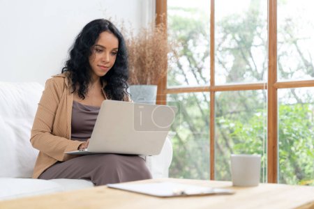 Photo for African-American woman using laptop computer for crucial work on internet. Secretary or online content writing working at home. - Royalty Free Image