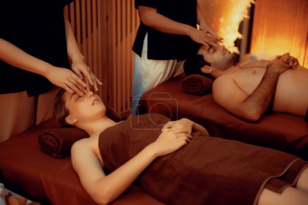 Photo for Couple customer enjoying relaxing anti-stress head massage and pampering facial beauty skin recreation leisure in warm candle lighting ambient salon spa in luxury resort or hotel. Quiescent - Royalty Free Image