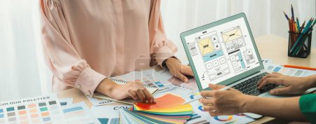 Photo for Cropped image of interior designer chooses color from color swatches while laptop displayed website wireframe designs for mobiles app and website. Creative design and business concept. Variegated. - Royalty Free Image