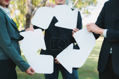 Photo for Business people holding pieces of reverse arrow icon into recycle symbol together in outdoor nature, promoting Earth cleaning day with zero waste pollution by embrace recycle reduce reuse idea. Gyre - Royalty Free Image