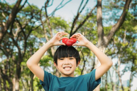Foto de Campaña de sensibilización ecológica que promueve la protección del medio ambiente con el feliz niño asiático sosteniendo el corazón como símbolo de amor por la naturaleza y la ecología para una Tierra sostenible más verde en el futuro. Gyre. - Imagen libre de derechos