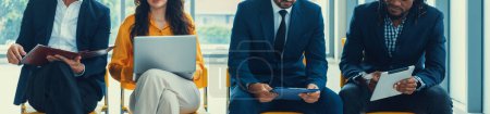 Photo for Diversity candidates siting while waiting for job interview in front view. Low section crop of interviewees sitting on a chair while preparing their document and holding their laptop. Intellectual. - Royalty Free Image