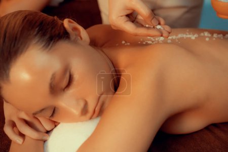 Photo for Closeup couple customer having exfoliation treatment in luxury spa salon with warmth candle light ambient. Salt scrub beauty treatment in Health spa body scrub. Quiescent - Royalty Free Image